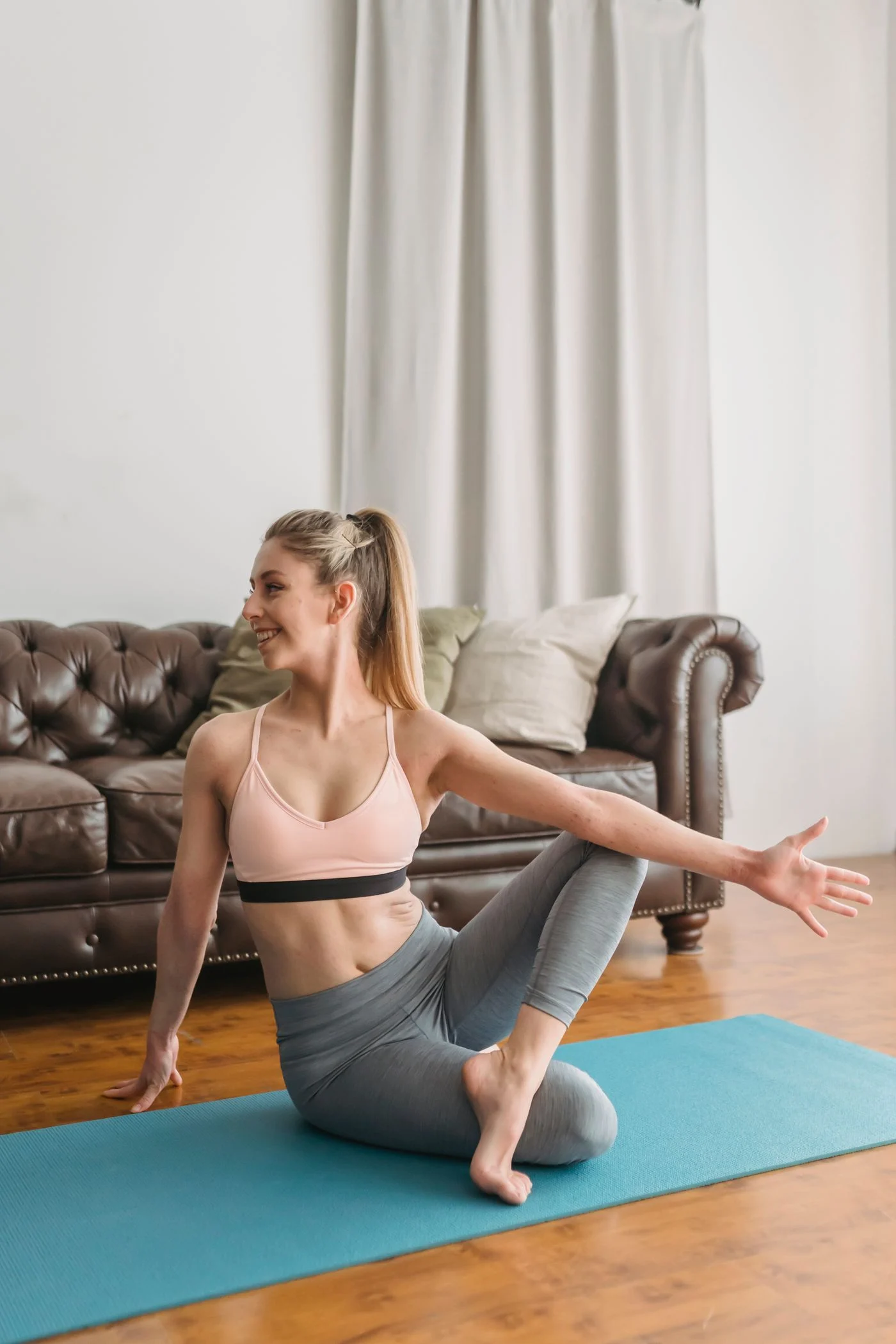 A woman stretching on a mat in a sunlit living room